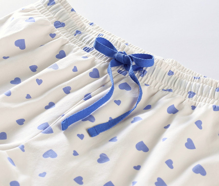 Detail krátkého pyžama se srdíčky a modrou stuhou.