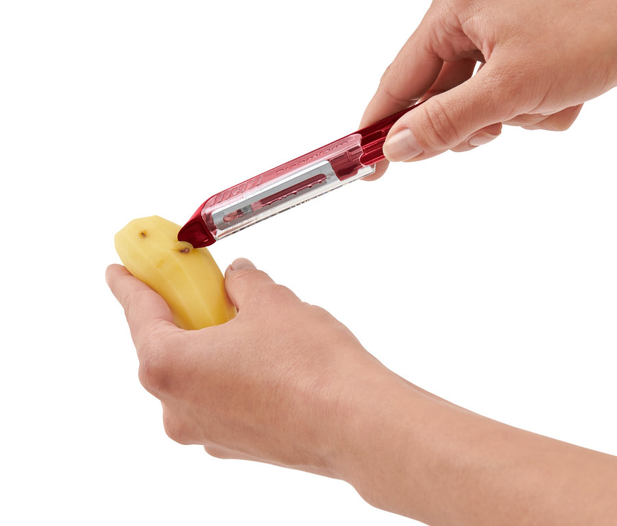 Osoba loupá bramboru pomocí univerzální samoostřící škrabky.