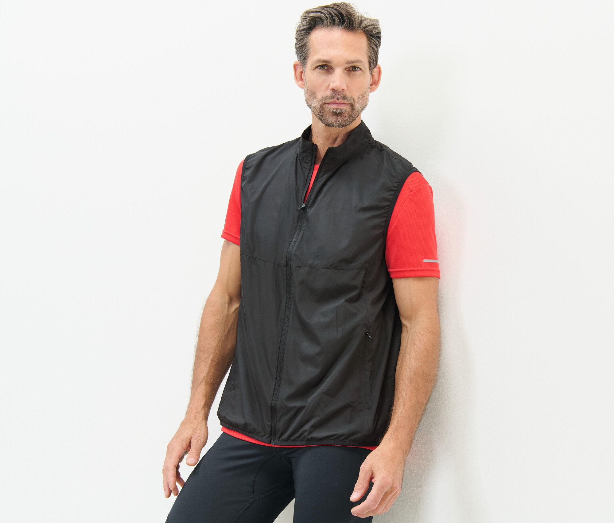 Muž opřený o stěnu má na sobě funkční vestu.
