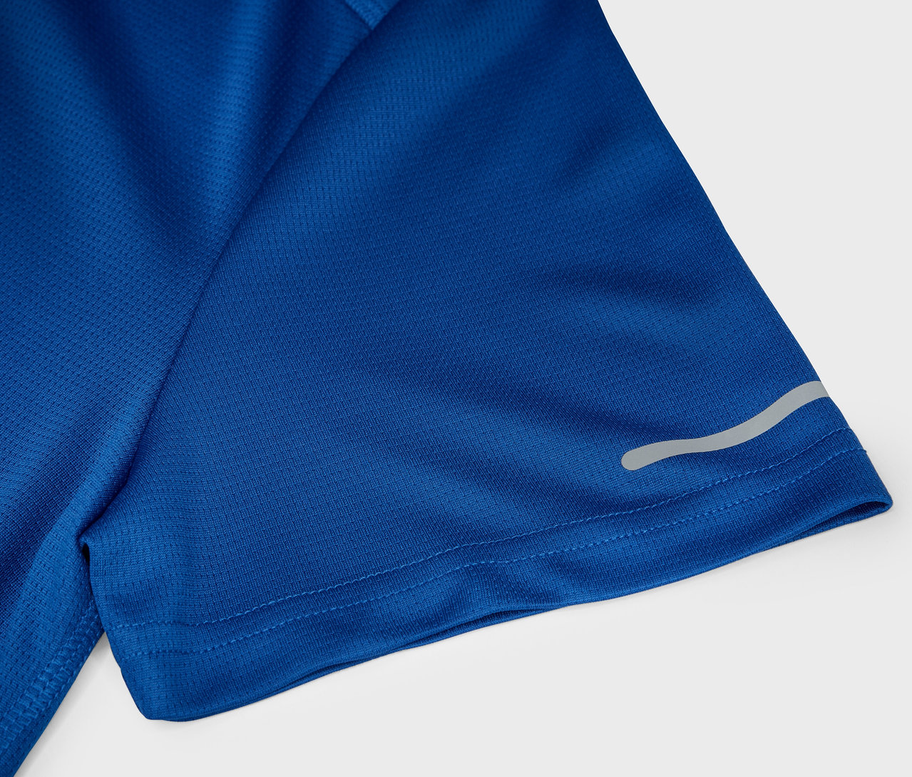 Detail modrého sportovního trička s krátkým rukávem a reflexním proužkem.