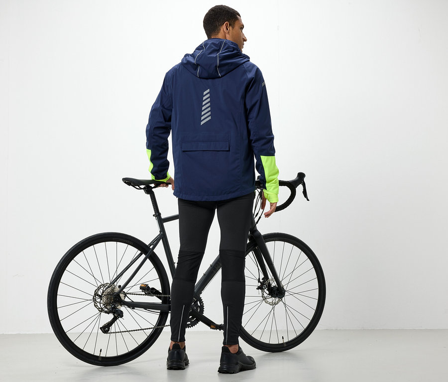 Muž v bundě s kapucí stojí vedle kola.