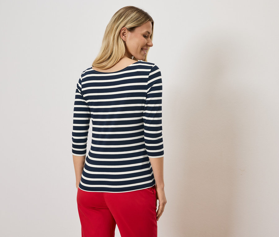 Blondýna v tričku s námořnickým vzorem a červených kalhotách.