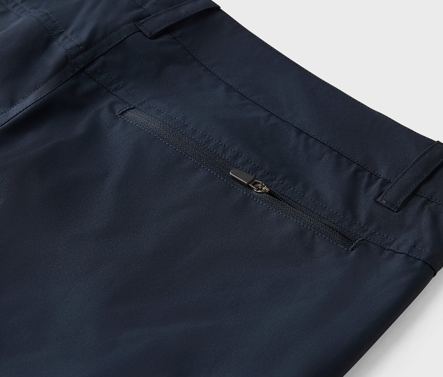 Detailní záběr na tmavě modré kalhoty s kapsou na zip.