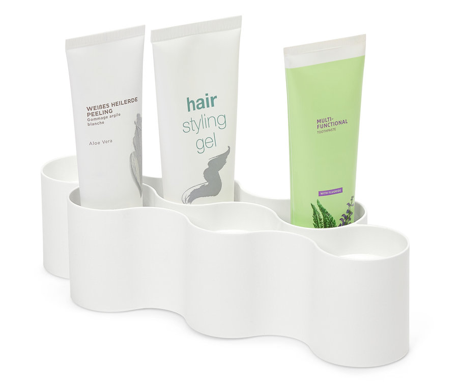 Tři tuby kosmetiky v bílém plastovém držáku.