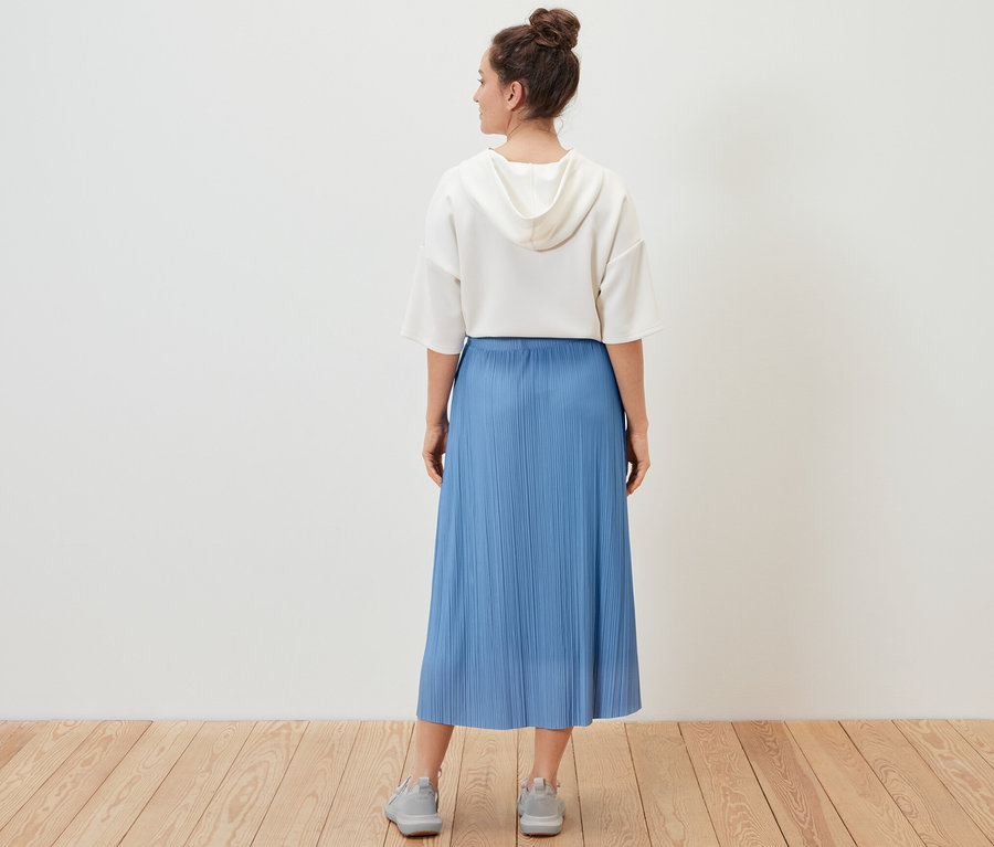 Žena má na sobě plisovanou sukni.