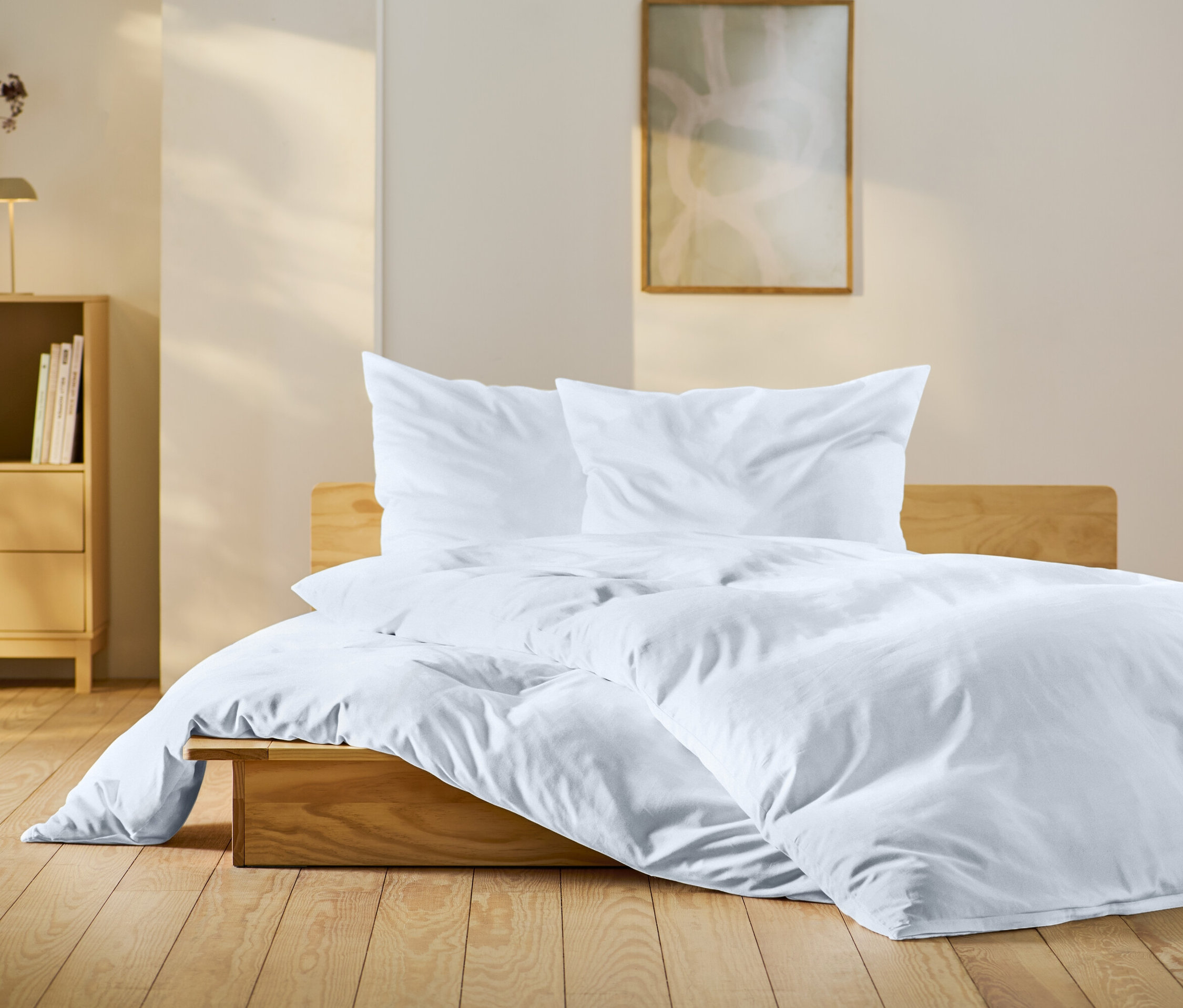 Ložnice s dřevěnou postelí s bílým povlečením, dřevěným nočním stolkem a dekoracemi.