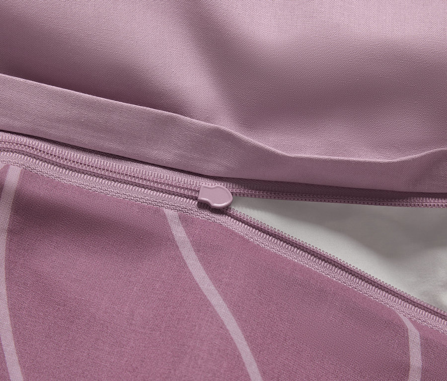 Detail fialového povlečení se zipem a bílým vnitřkem.