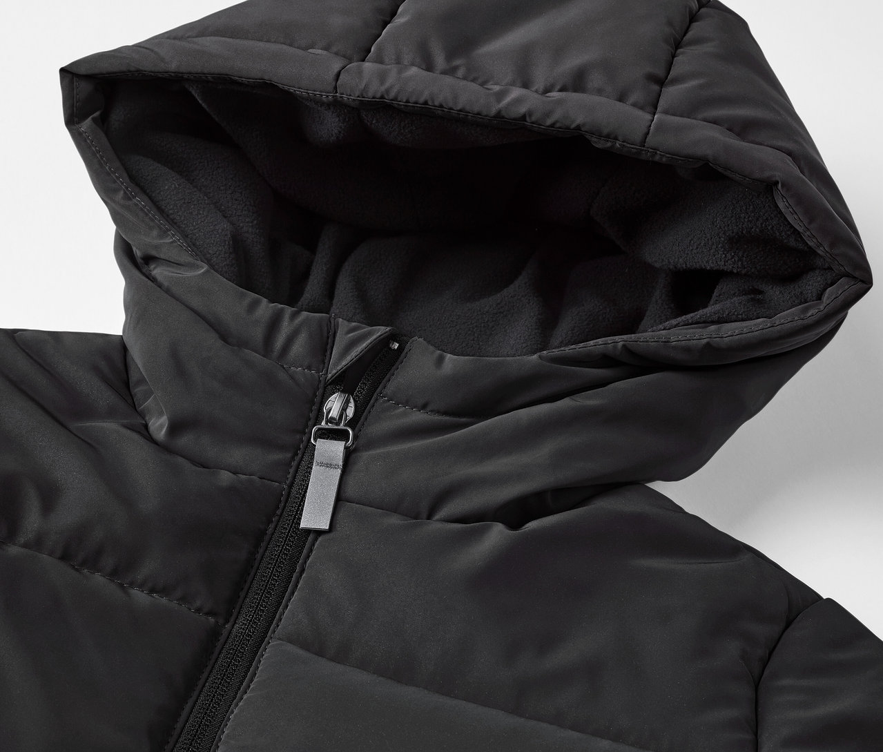 Detail černé dětské prošívané bundy s reflexními prvky.