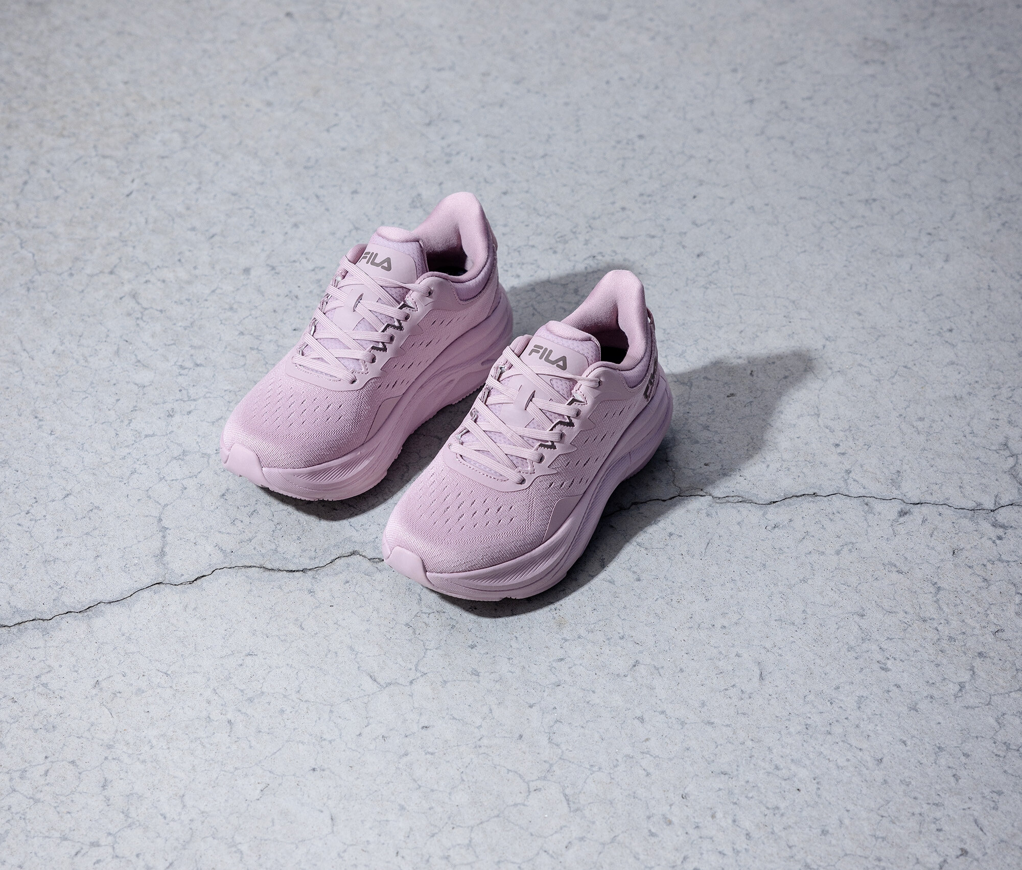 Dvě fialové běžecké boty Fila stojí na šedém pozadí.
