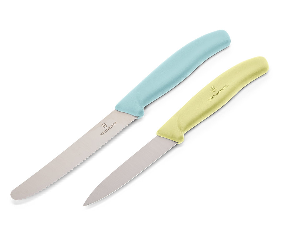 Dva nože Victorinox leží diagonálně na bílém pozadí. Horní nůž má světle modrou rukojeť a zoubkovanou čepel, dolní nůž má světle žlutou rukojeť a hladkou čepel.