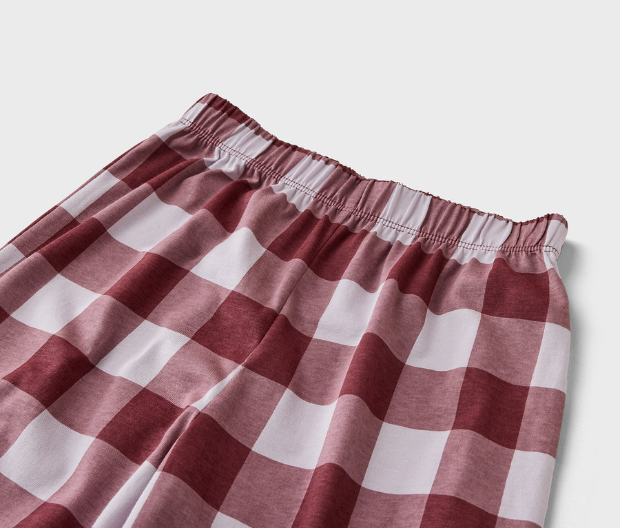 Detailní záběr kalhot s elastickým pasem a červeno-bílým kostkovaným vzorem.