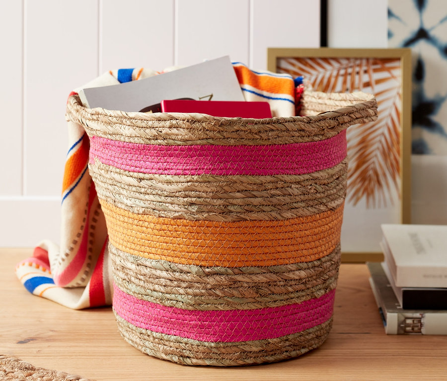 Proutěný dekorační košík s růžovými a oranžovými pruhy.