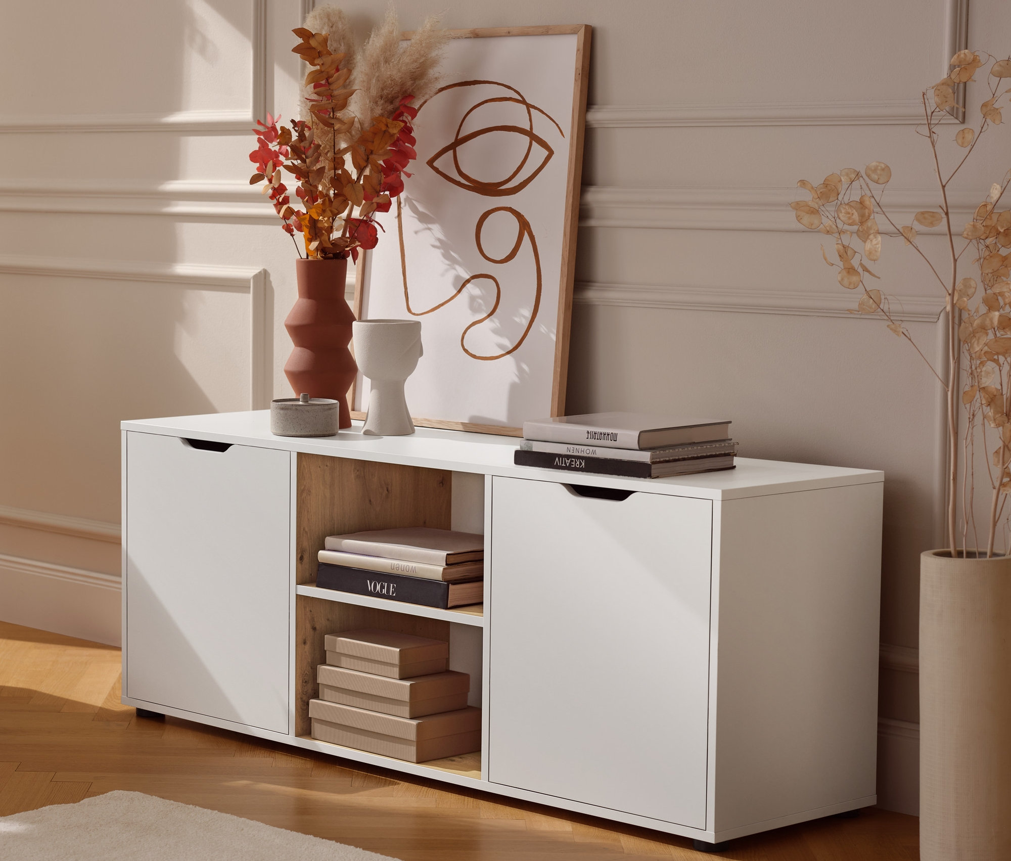 Kovový odkládací stolek stojí vedle nízké skříňky se zásuvkami.