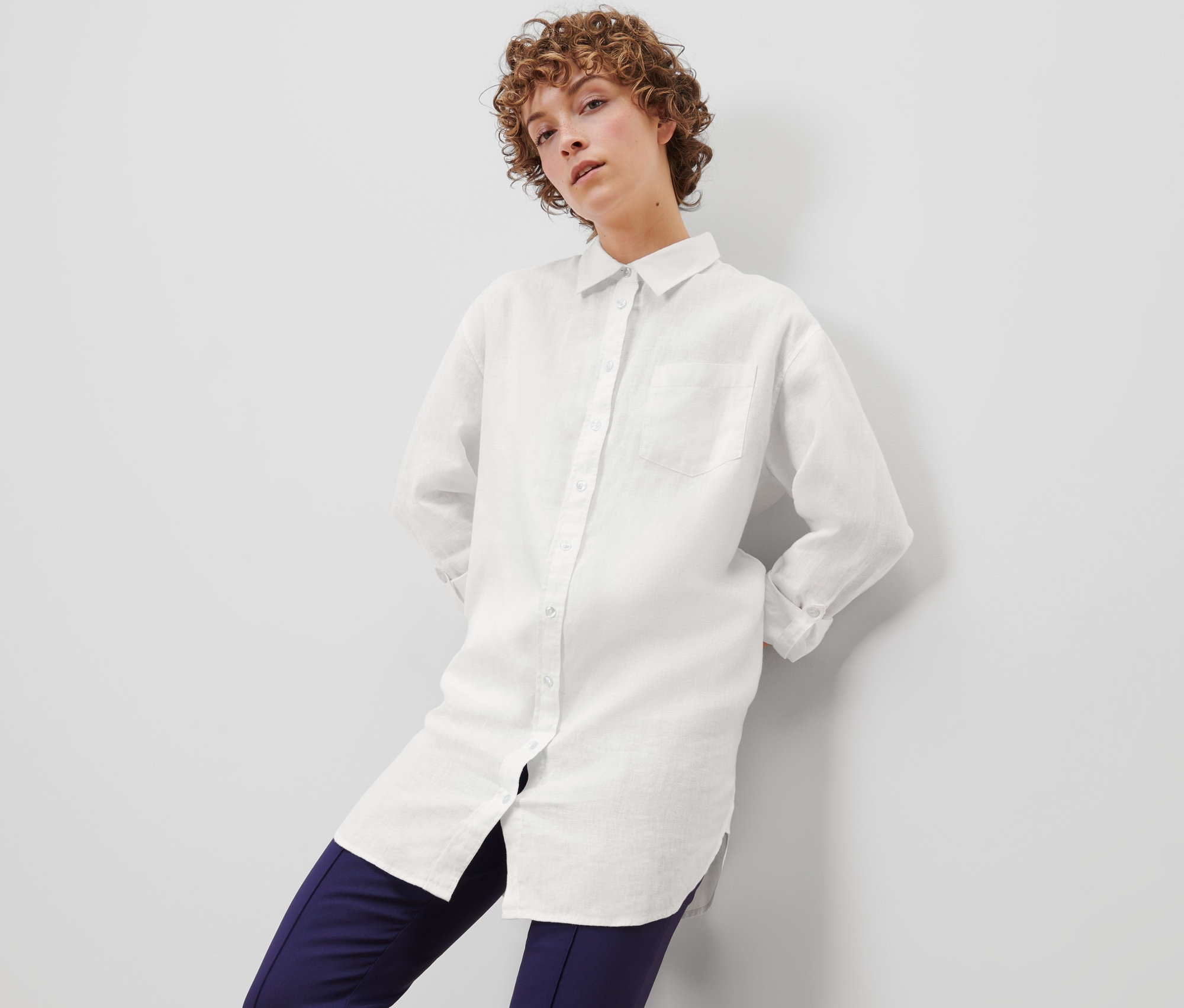 Žena pózuje v bílé lněné halence.