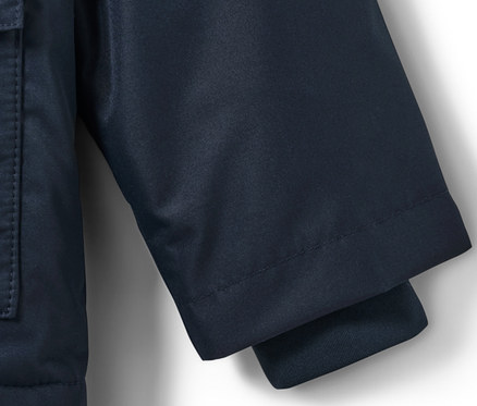 Detail dětské termo bundy do deště s motivem pejska, ukazující rukáv a kapsu.