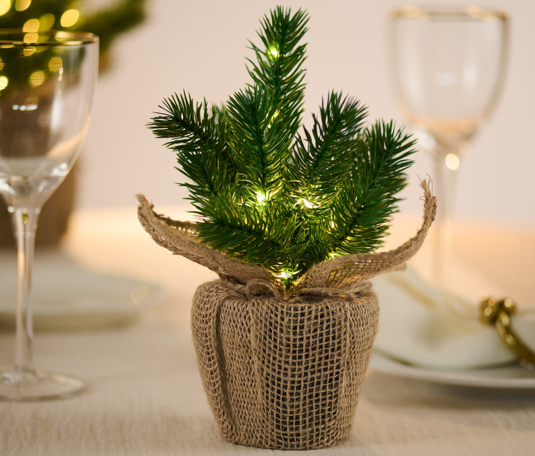 Malý vánoční stromek s LED diodami stojí na stole.