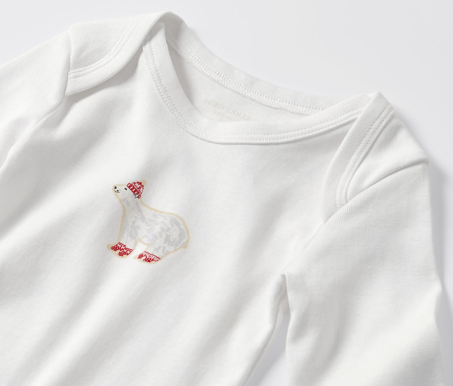 Detail dětského body s dlouhým rukávem s motivem medvěda s červenou čepicí a ponožkami.