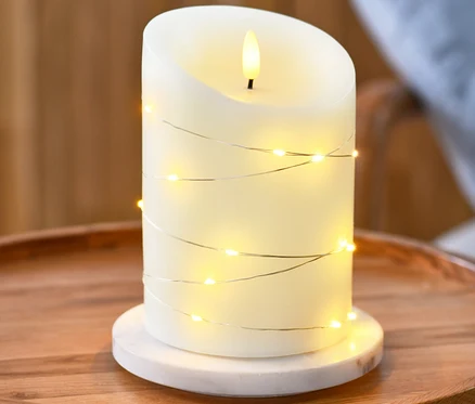 LED svíčka z pravého vosku s mikro LED světelným řetězem na kulatém dřevěném stolku.