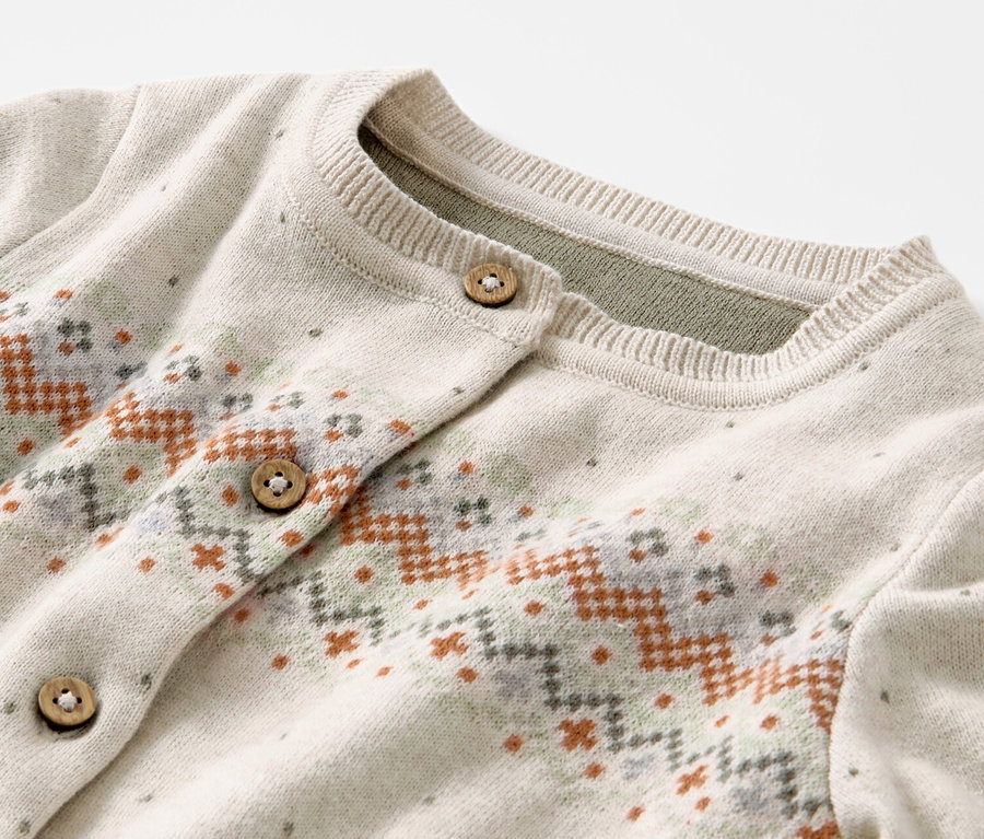 Detail dětského pleteného svetru s norským vzorem a dřevěnými knoflíky.