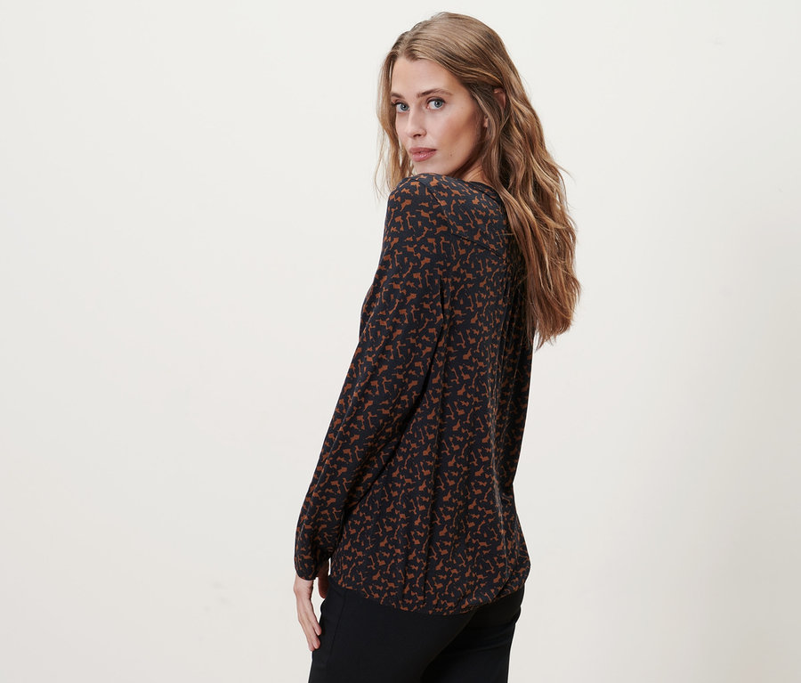 Žena se dívá přes rameno a má na sobě halenkové triko s potiskem.