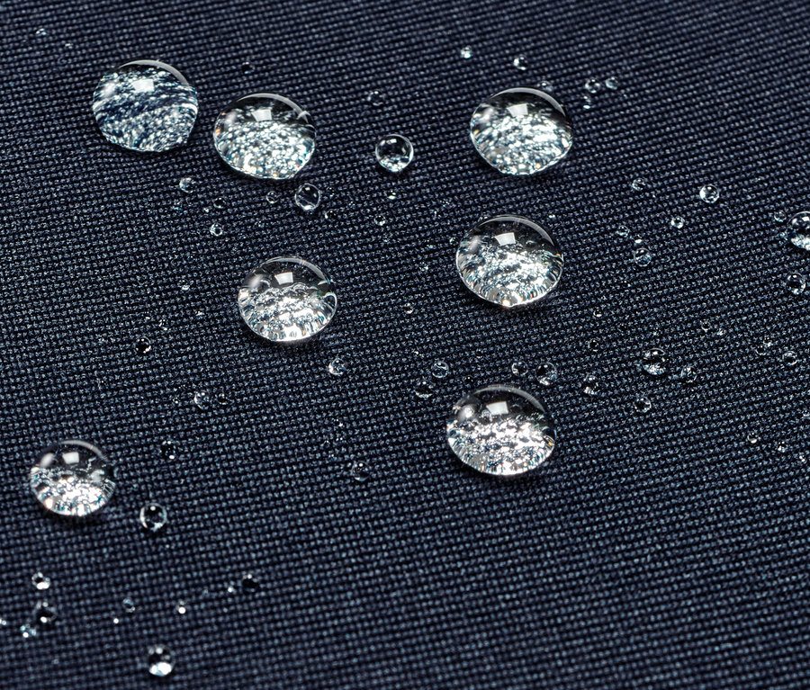 Detailní záběr vodoodpudivých sportovních legín s kapkami vody na povrchu.