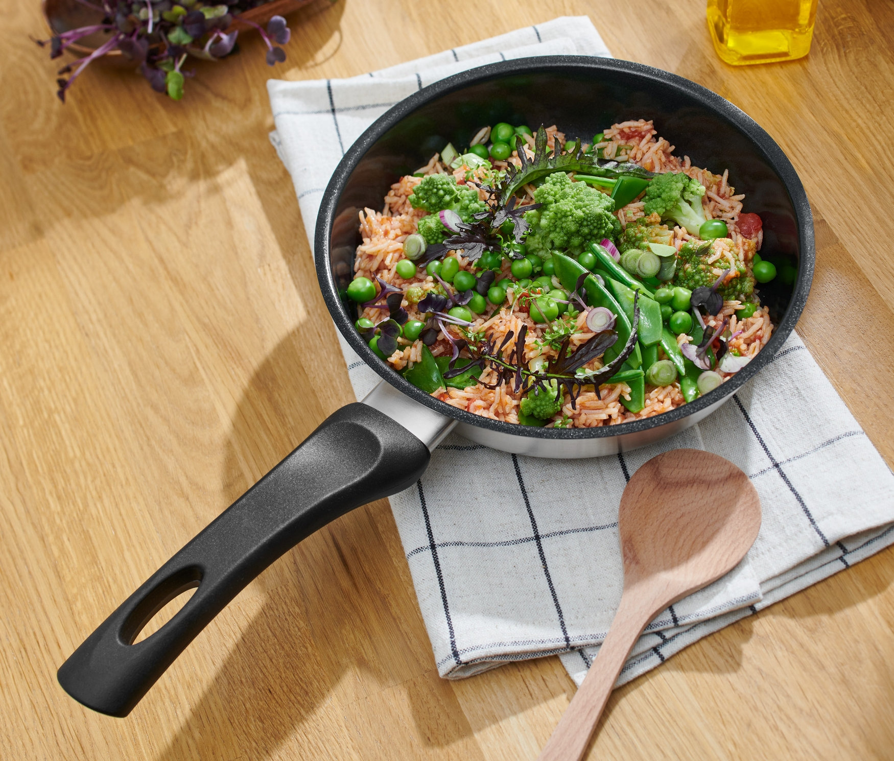 Nerezová pánev s keramickým povrchem, průměr cca 20 cm, s jídlem na kostkované utěrce.