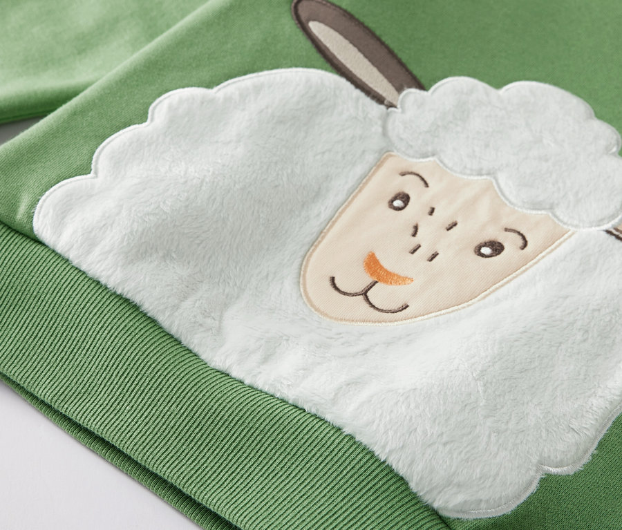 Detail zelené dětské mikiny s vnitřní stranou s aplikací ovce.