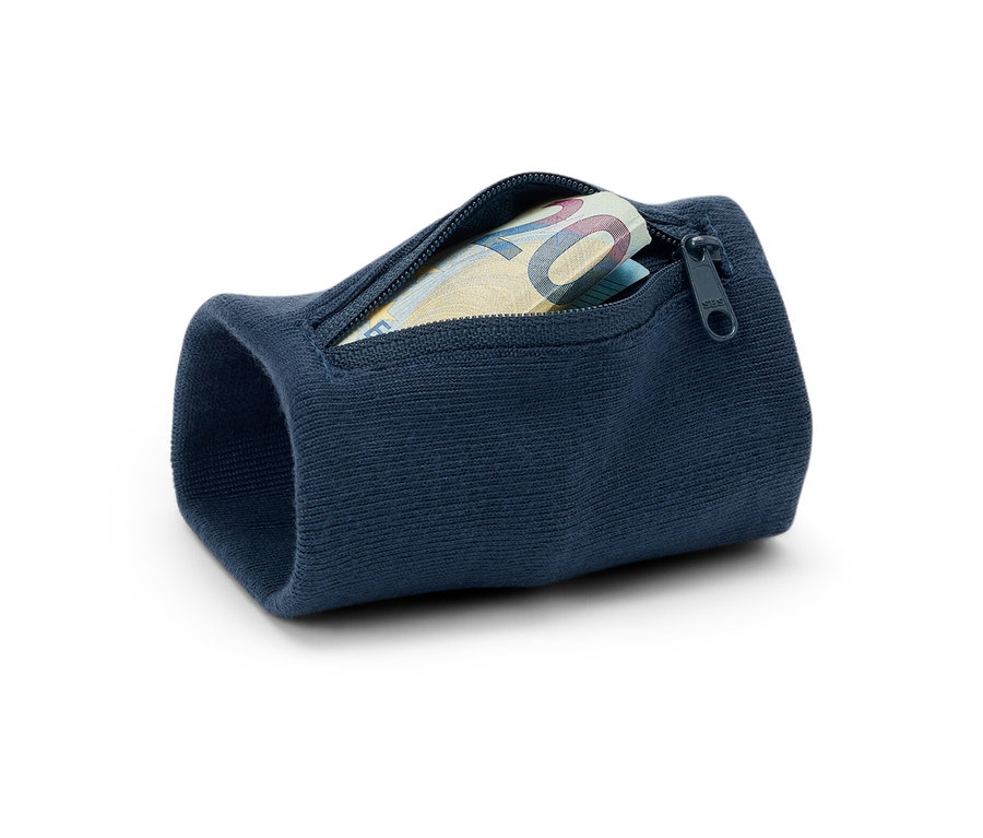 Detail modré bezpečnostní peněženky na zápěstí s dvacetieurovou bankovkou. Peněženka leží na bílém pozadí.