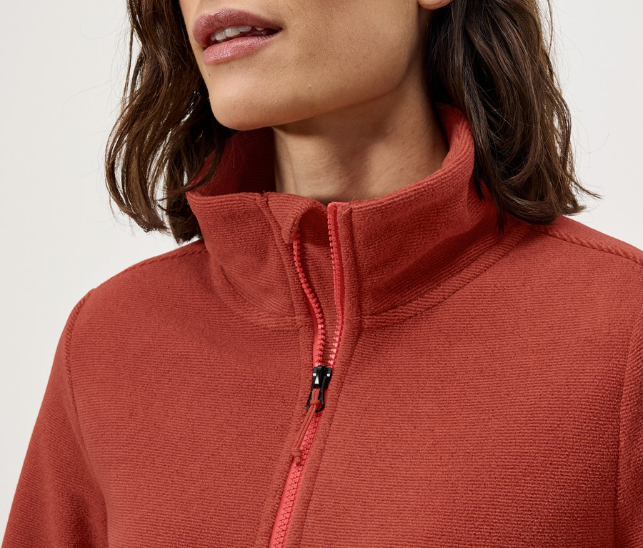 Detail dámské fleecové mikiny s límcem a zipem.