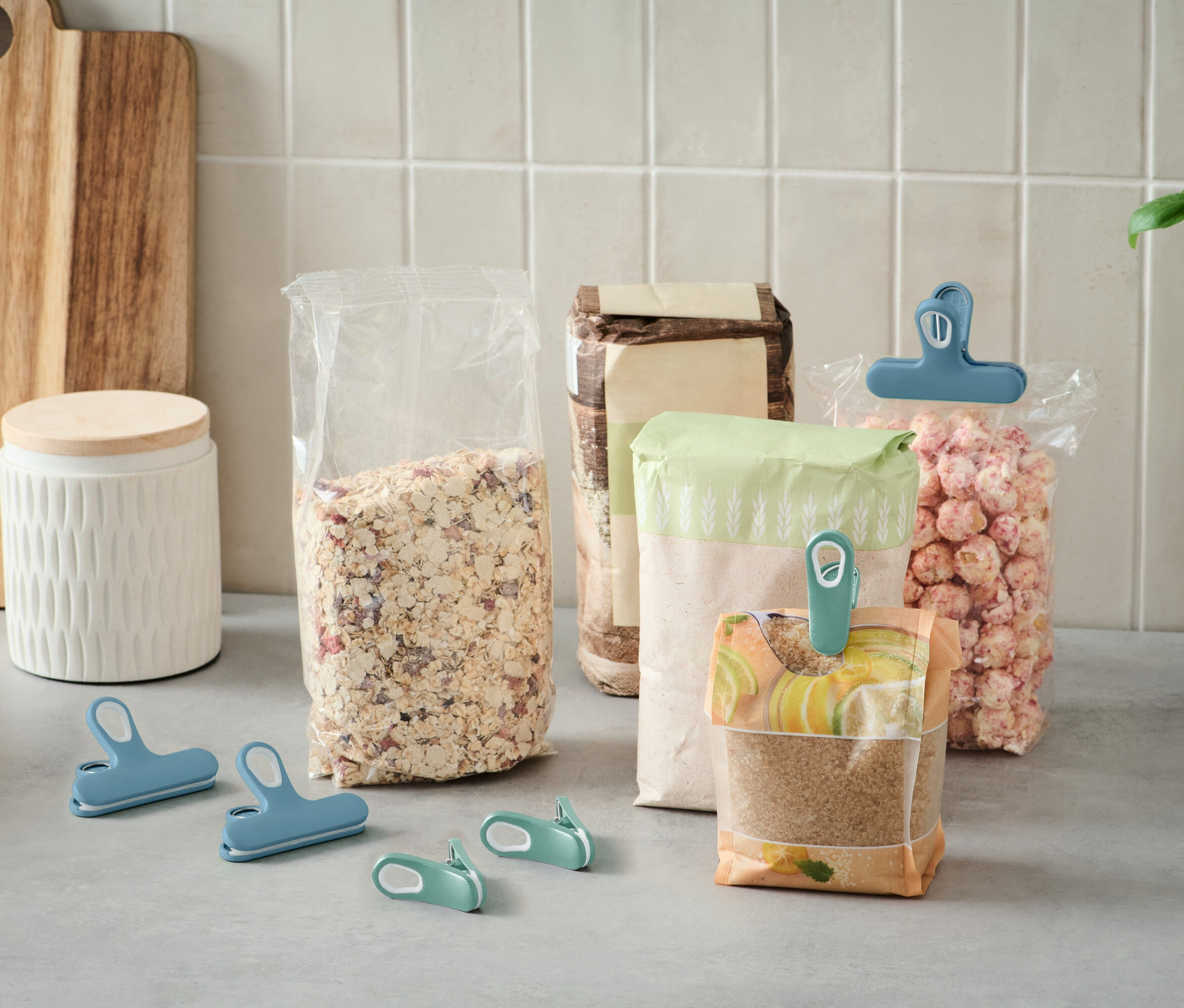 Na lince stojí několik otevřených sáčků s jídlem, které jsou uzavřeny barevnými klipy.