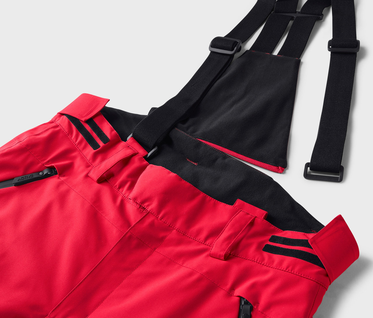 Detail červených lyžařských kalhot s černými šlemi.