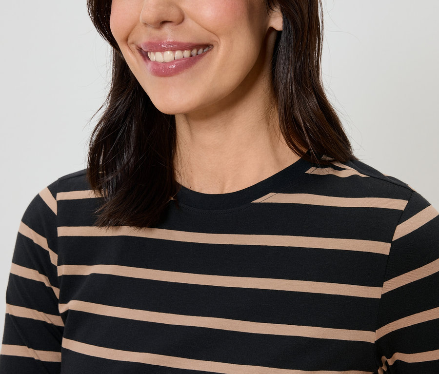 Usmívající se žena s tmavými vlasy má na sobě pruhované tričko.