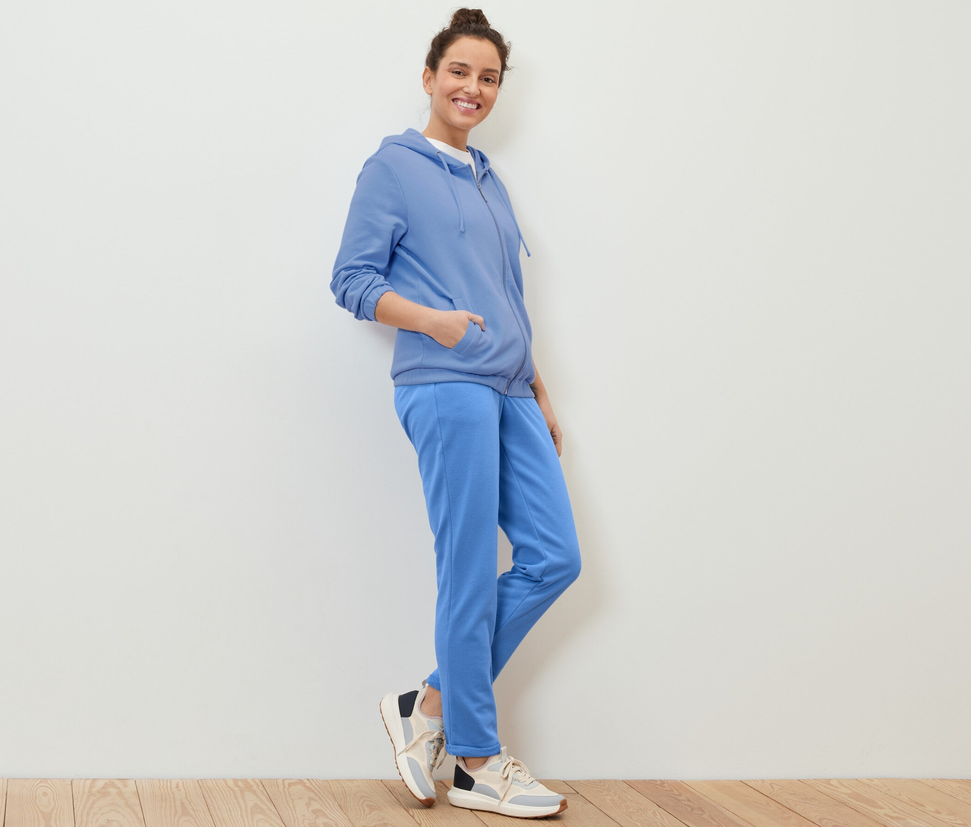 Žena pózuje v svetle modré mikině.