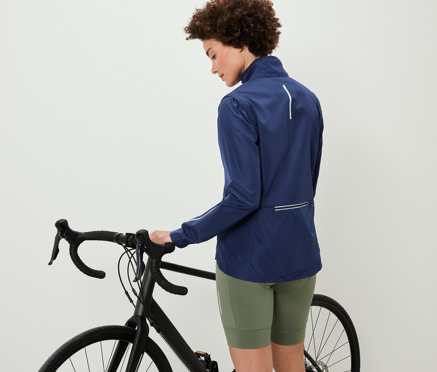 Žena stojí vedle kola a má na sobě cyklistickou bundu 2 v 1.