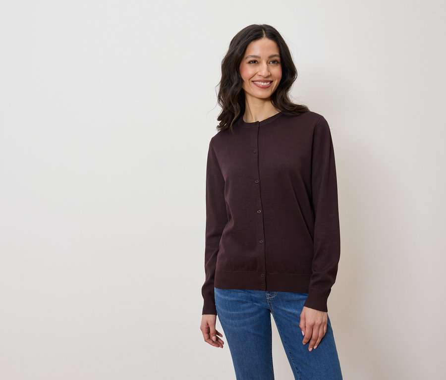 Žena má na sobě tmavě fialový kardigan a džíny.