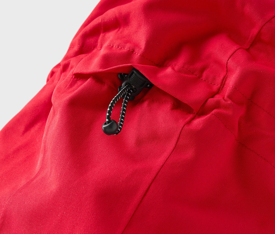 Detail červené bundy s kapucí a stahovací šňůrkou.