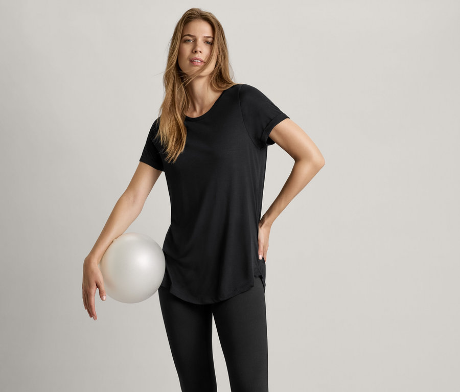 Žena drží míč a má na sobě černé dlouhé tričko.