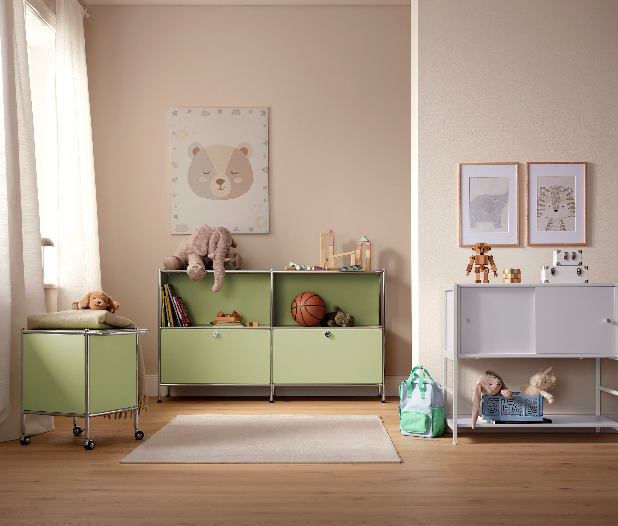 Dětský pokoj se světle zelenými a bílými úložnými skříněmi, hračkami a obrázky na zdi.