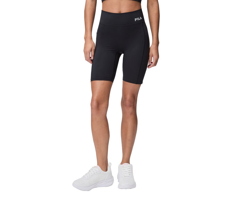 Žena má na sobě černé cyklistické šortky Fila a bílé tenisky.