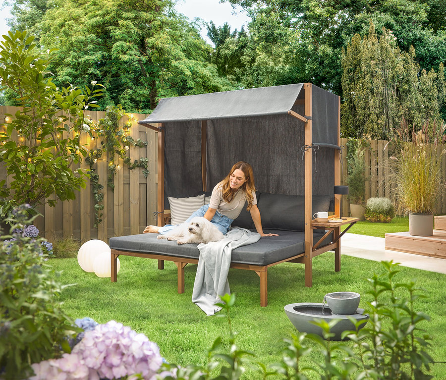 Žena sedí se psem na solární zahradní fontáně na zahradě.