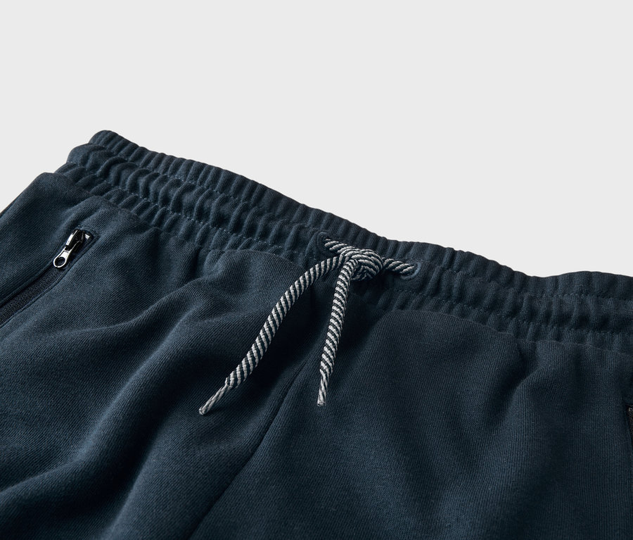 Detailní záběr na tmavě modré tepláky se stahovací šňůrkou a kapsou na zip.