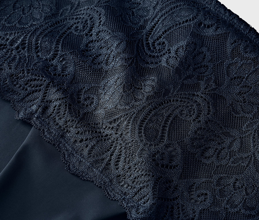 Detail modré krajky na modré látce.