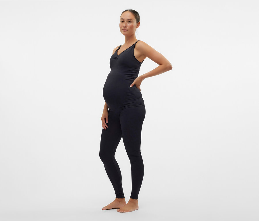 Těhotná žena v černém topu a skinny legínách MAMALICIOUS »MLTIA JEANNE« pózuje bokem.