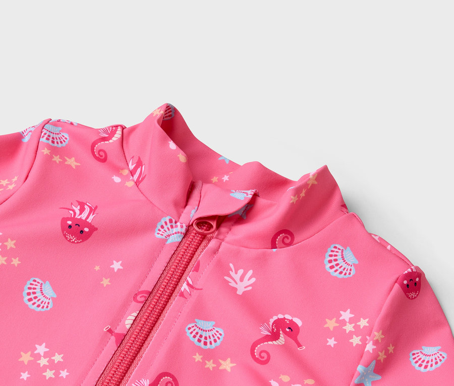 Detailní záběr na růžové plavky na zip se vzorem mořských koníků, mušlí a hvězd.