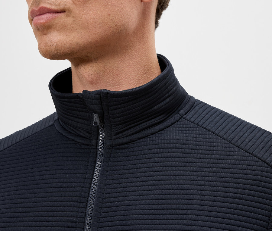 Detail muže v tmavě modré bundě na zip se stojáčkem.