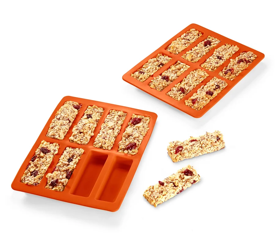 Dvě oranžové formy na pečení müsli tyčinek, 2 ks, jedna plná tyčinek a dvě tyčinky vedle.