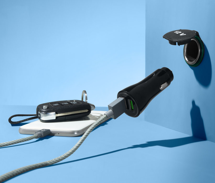 Na modrém pozadí je vidět USB rozbočka do auta zapojená do zásuvky 12V. K mobilnímu telefonu je připojený kabel.