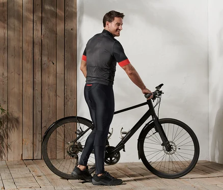 Muž stojí vedle kola a má na sobě cyklistické kalhoty.