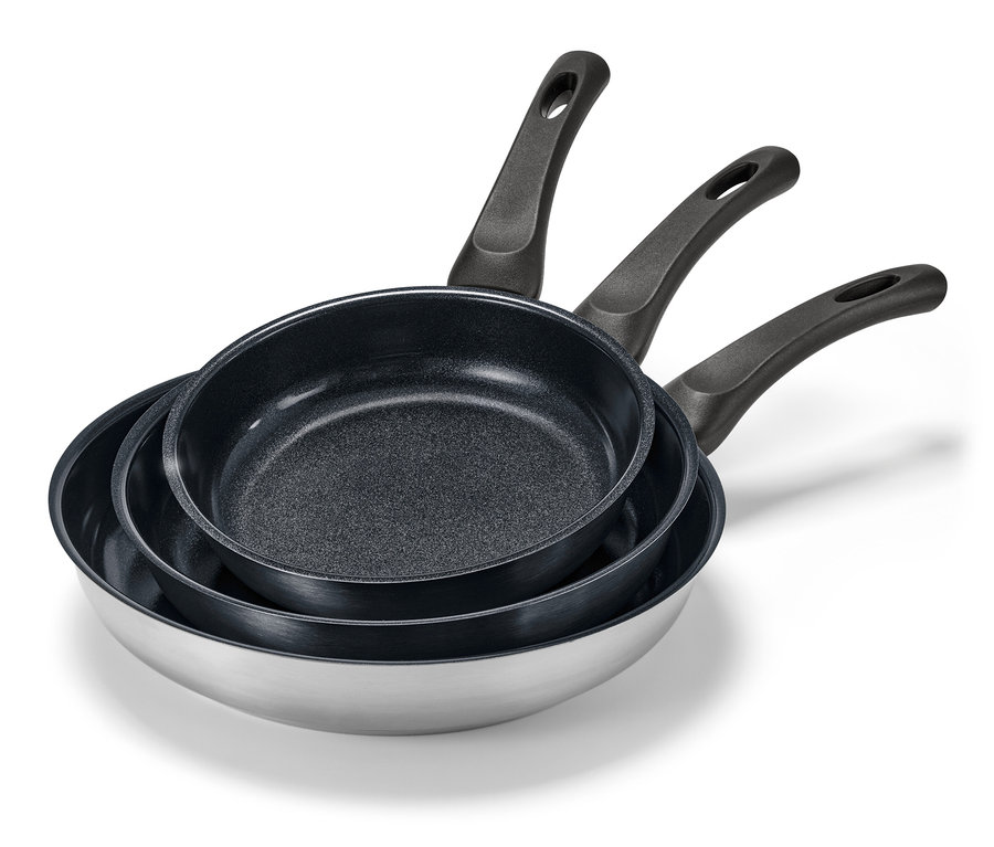 Tři pánve z ušlechtilé oceli s keramickým povrchem různých velikostí naskládané na sobě.