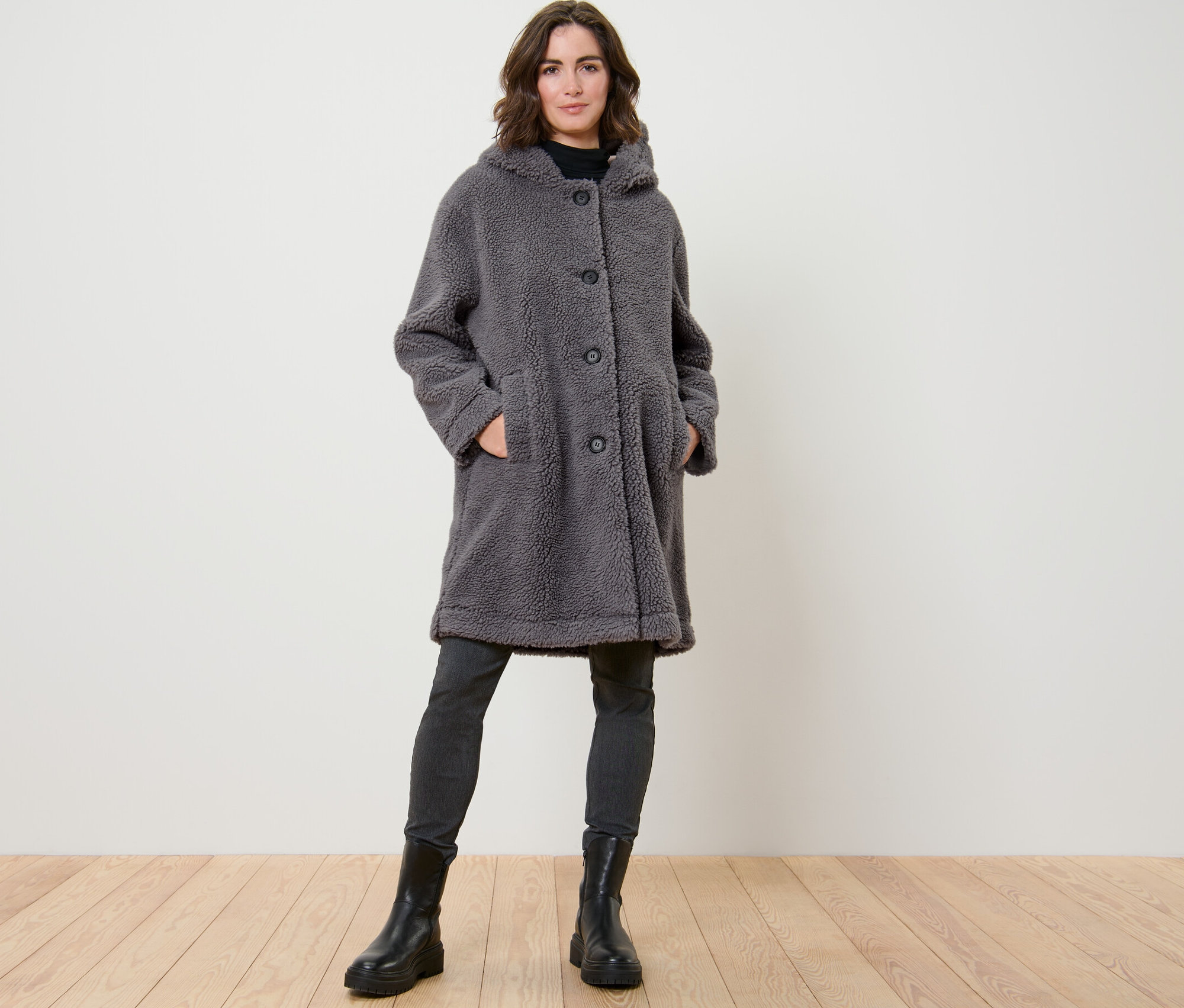 Žena pózuje v plyšovém kabátu s kapucí.